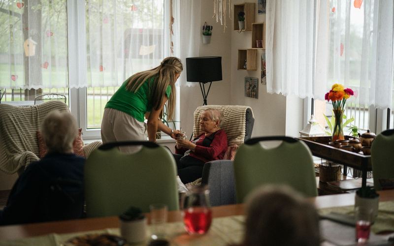 Professional carer assisting an older resident in a care home